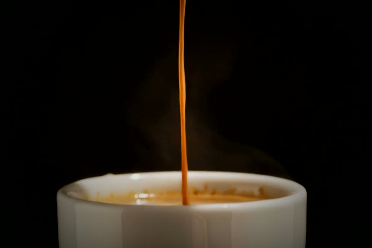 A frame from the Still Dark film: an espresso pouring into the cup, in the dark.