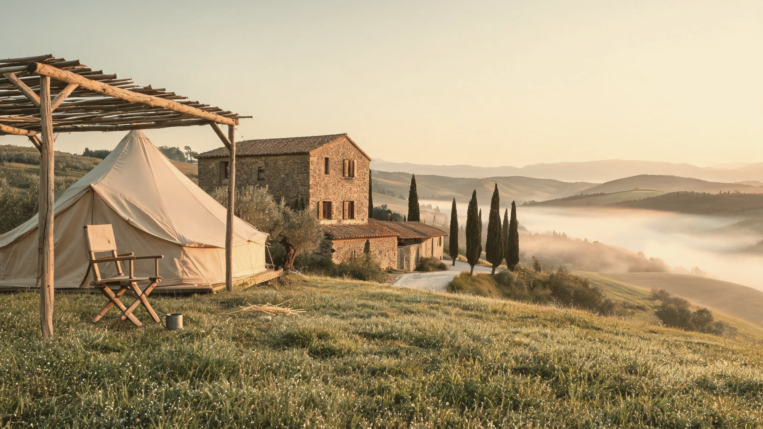 A canvas bell tent under a timber shade roof at dawn, the valley in mist beyond