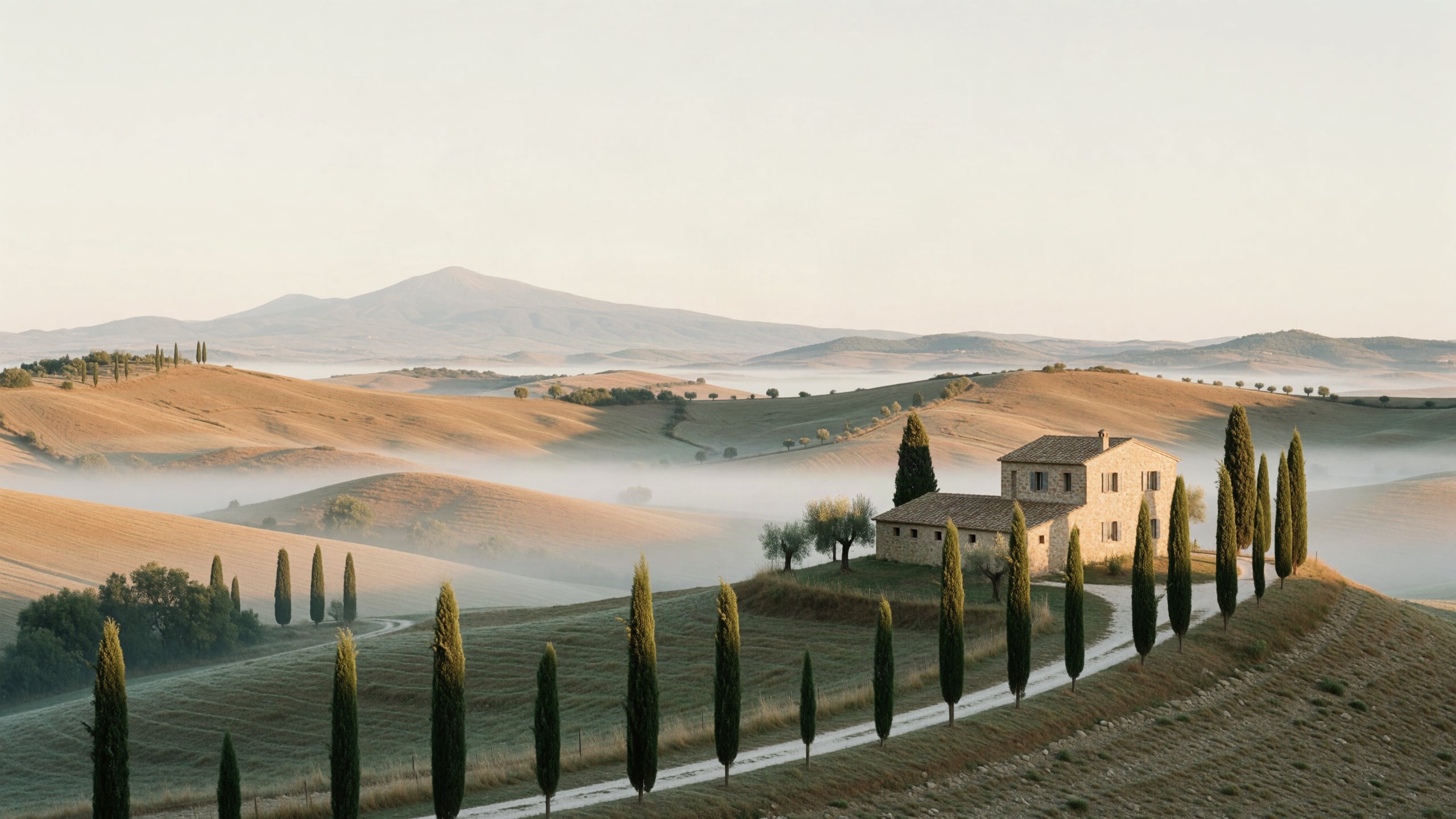 Soft morning light over layered hills, a farmhouse and a line of cypresses
